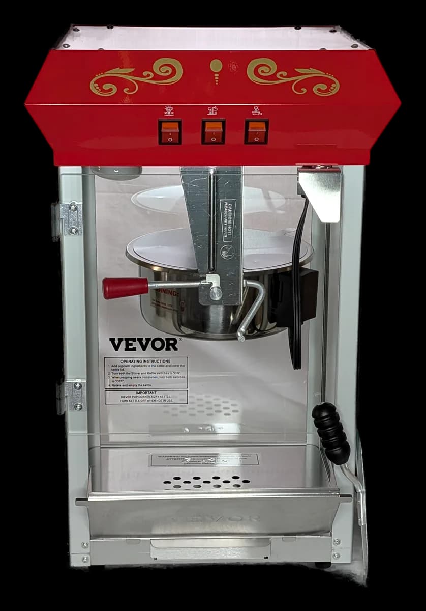 Red and gold commercial popcorn machine with a glass cabinet and a kettle inside